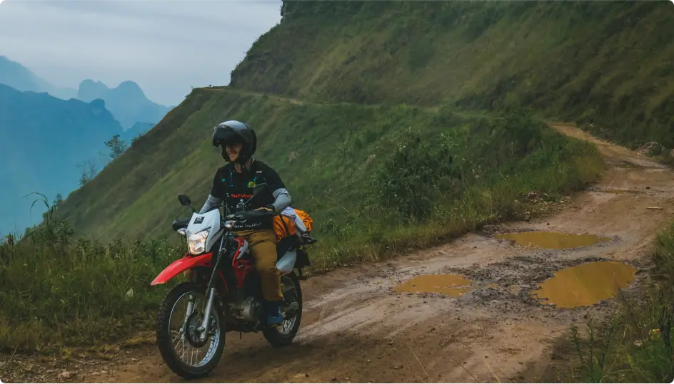 A man riding a Honda XR 150 motorcycle along a mountain road in Ha Giang