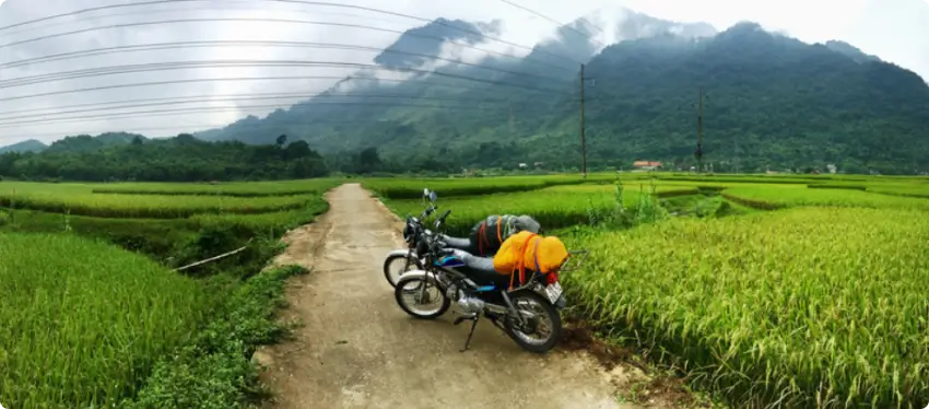 Two Detech Honda Win motorcycles parked on a road in Northern Vietnam with mountains in the background