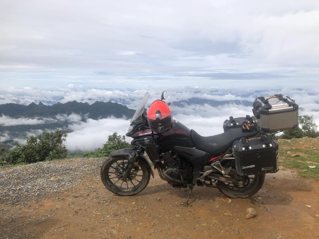 Two Detech Honda Win motorcycles parked on a road in Northern Vietnam with mountains in the background