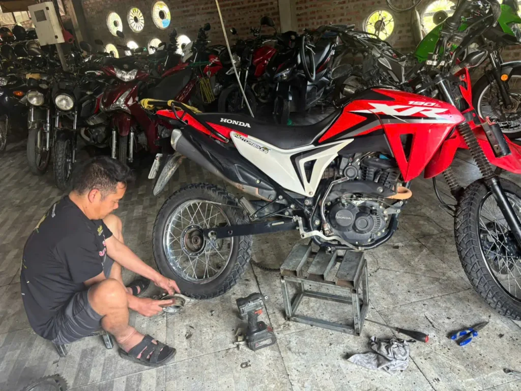 Ha Giang Loop: Why Bike Quality Matters (Your Safety Guide) 4 style motorbikes in house mechanics in ha giang shop working on a honda xr 190
